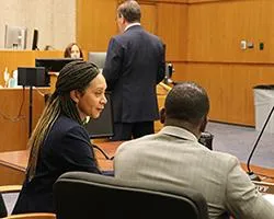 Attorney speaking with a client in a courtroom.